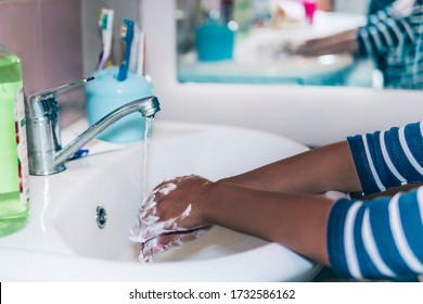 Cropped image of person washing hands at sink in bathroom, Coronavirus hand washing for clean hands hygiene Covid-19 spread prevention viral, bacterial infections. African-American girl washes hands.