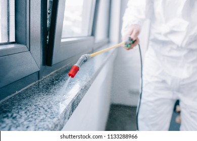 Cropped Image Of Pest Control Worker Spraying Pesticides On Windowsill At Home