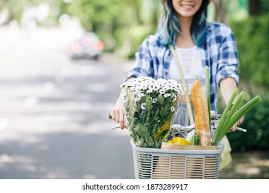 Cropped Image Of Positive Young Woman Sitting On Bicycle With Bouquet And Groceries In Front Basket