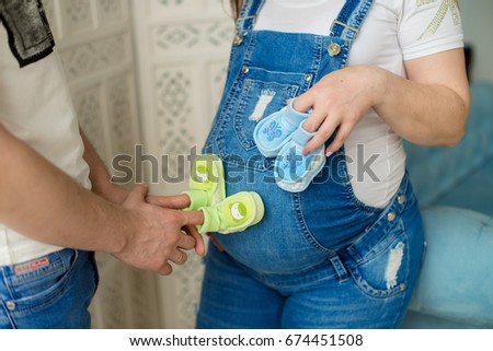 Cropped image of pregnancy woman and her husband holding baby shoes. Close up. Concept of a happy family