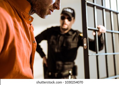 Cropped Image Of Prison Guard Looking At Criminal In Prison Cell