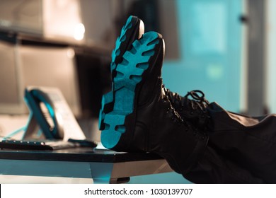 Cropped Image Of Prison Guard Sitting With Legs On Table