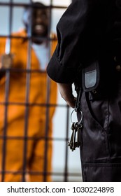 Cropped Image Of Prison Guard Standing Near Prison Bars With Keys