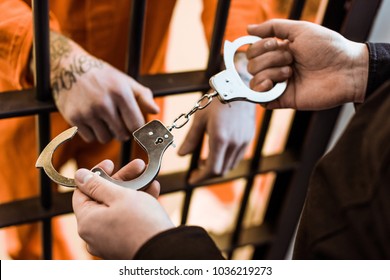 Cropped Image Of Prison Officer Wearing Handcuffs On Prisoner