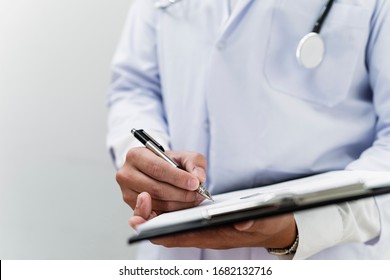 Cropped image of progress note on clipboard in doctor's hands while he write the patient's condition.