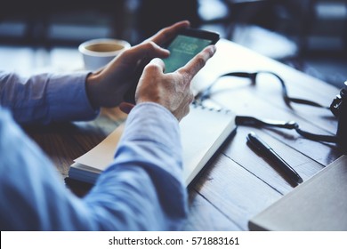 Cropped Image Of Prosperous Man Holding Smartphone Using Application To Booking Suite In Luxury Hotel For Business Trip Using Wireless Connection To Internet Resting In Cafe Interior Drinking Coffee