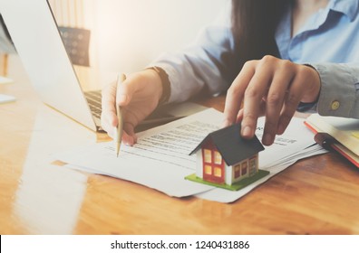 Cropped image of real estate agent assisting client to sign contract paper at desk with house model - Shutterstock ID 1240431886