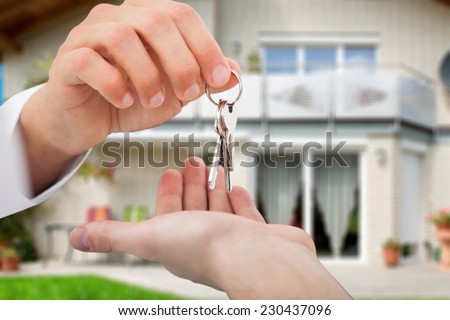 Cropped image of real estate agent giving keys to owner against new house