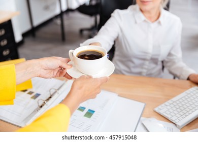 Cropped Image Of Secretary Bringing Cup Of Coffee For Her Boss In Office