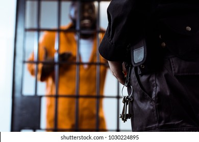 Cropped Image Of Security Guard Standing Near Prison Bars With Keys