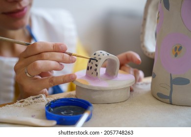 Cropped image of self employed ceramist craftswoman drawing decoration on ceramic cup for clay jug during master class in pottery studio. Creative occupation in workshop. Relax with handicraft concept - Powered by Shutterstock