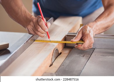 Cropped image of senior carpenter measuring wood at tablesaw in workshop - Powered by Shutterstock