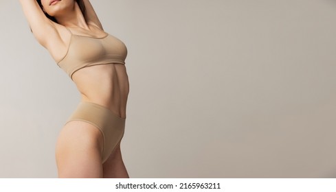 Cropped image of slim female body in beige underwear isolated over grey studio background. Well-being. Feeling good. Concept of beauty, body and skin care, health, spa, cosmetics, ad