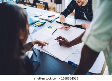 Cropped image of smart casual group of millennials collaborating on information for paper sketch doing brainstorming togetherness, young productive students preparing to examination indoors