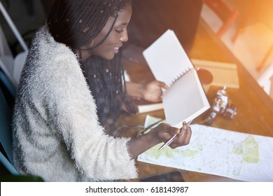 Cropped image of smiling afro american hipster girl reading notebook with mock up space for your advertising text message sitting indoors while selecting route on map for new journey during good day - Shutterstock ID 618143987