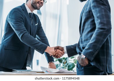 cropped image of smiling multicultural businessmen shaking hands in office