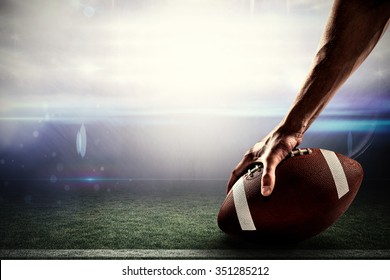 Cropped image of sports player holding ball against american football arena
