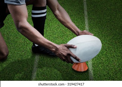 Cropped image of sportsman keeping rugby ball on kicking tee against pitch with lines - Powered by Shutterstock