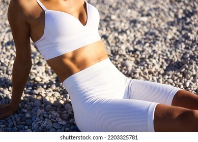 Cropped image of strong fit female body with well- defined abs in white sports wear. High quality photo - Powered by Shutterstock