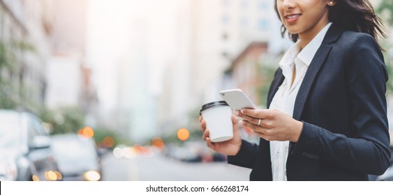 Cropped Image Of Successful Business Woman Wearing Suit Using Modern Smartphone And Drinking Coffee To Go Before Going To Work Early In The Morning