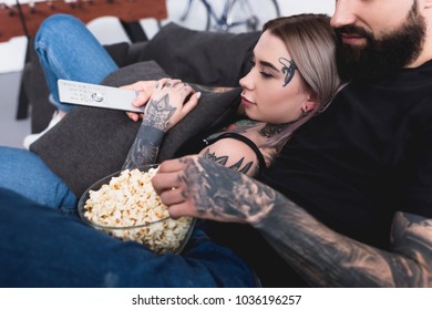 Cropped Image Of Tattooed Couple Watching Tv With Popcorn At Home