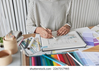 Cropped image of unrecognizable female architect or designer draws apartment design with art tools poses at table wears striped jumper and smartwatch busy working. Creative people workplace. - Powered by Shutterstock