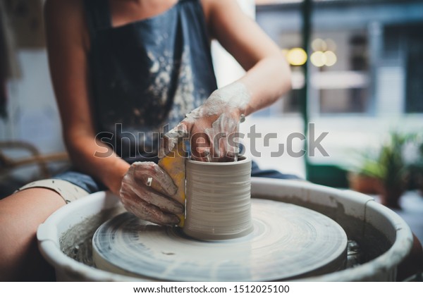 Cropped Image of Unrecognizable\
Female Ceramics Maker working with Pottery Wheel in Cozy Workshop\
Makes a Future Vase or Mug, Creative People Handcraft Pottery Class\
