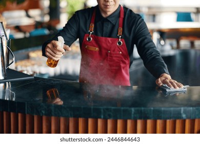 Cropped image of waiter cleaning bar counter with disinfecting spray - Powered by Shutterstock