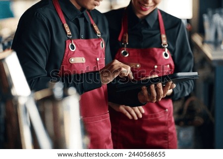 Cropped image of waiters checking new restaurant menu on tablet computer
