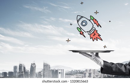 Cropped image of waitress's hand in white glove presenting sketched flying missile on metal tray with cityscape view on background. - Powered by Shutterstock