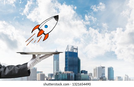 Cropped image of waitress's hand in white glove presenting sketched flying missile on metal tray with cityscape view on background. - Powered by Shutterstock