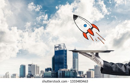 Cropped image of waitress's hand in white glove presenting sketched flying missile on metal tray with cityscape view on background. - Powered by Shutterstock