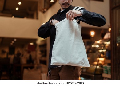 Cropped Image Of White Canvas Bag While The Guy Open And Find Something Inside.