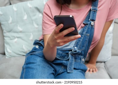 Cropped Image Of Woman With Bib Overalls Using Phone