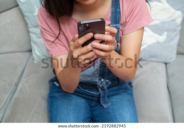 Cropped Image Of Woman with Bib Overalls using\
phone on coach