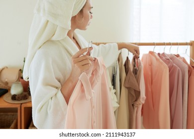 Cropped image of woman choosing clothes to wear after morning shower - Shutterstock ID 2111943137