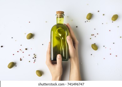 Cropped image of woman holding glass bottle of olive oil in hands isolated on white 