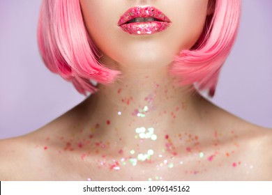 cropped image of woman with pink hair and glitter on lips and neck isolated on violet