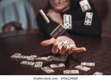 Cropped image of woman playing dominoes at table. Young adults playing the game of Domino with emotions. Scatter or throw away the pieces.