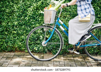 Cropped Image Of Woman Riding Bicycle With Basket Of Fresh Groceries