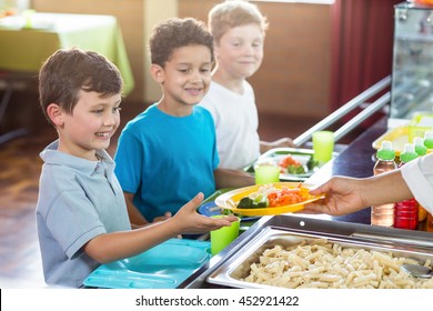 Cropped image of woman serving food to schoolchildren in canteen - Powered by Shutterstock