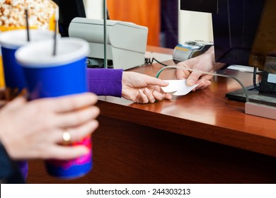 Cropped Image Of Women Holding Drinks While Buying Movie Tickets From Seller At Box Office