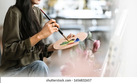 Cropped image of young beautiful artist girl sitting in front the drawing canvas while painting an oil color at the modern studio. Beautiful artist and gallery studio concept. - Powered by Shutterstock