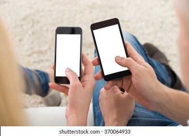 Cropped Image Of Young Couple Using Smart Phones With Blank Screens At Home