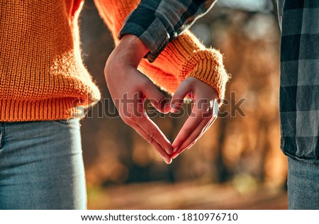 Photo of Cropped image of young couple walking in park in autumn time. 