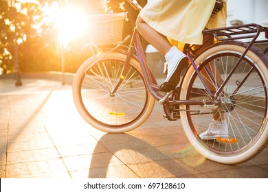 Cropped image of a young female in dress riding bicycle outdoors - Shutterstock ID 697128610