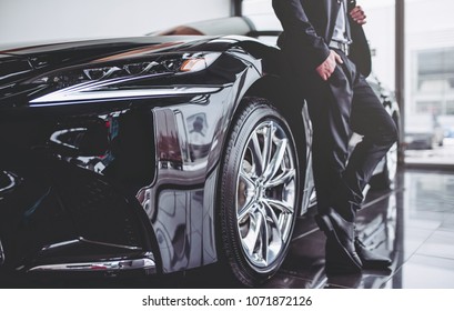 Cropped image of young handsome businessman in suit is standing near car. - Shutterstock ID 1071872126