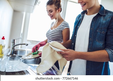 Cropped image of young happy couple is washing dishes while doing cleaning at home. - Shutterstock ID 772667146