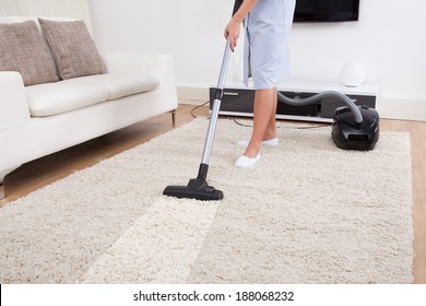 Cropped Image Of Young Maid Cleaning Carpet With Vacuum Cleaner At Home