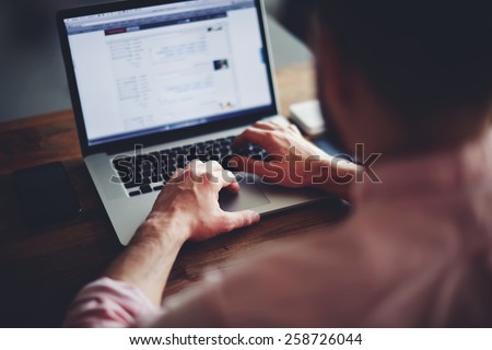 Cropped image of a young man working on his laptop in a coffee shop, rear view of business man hands busy using laptop at office desk, young male student typing on computer sitting at wooden table